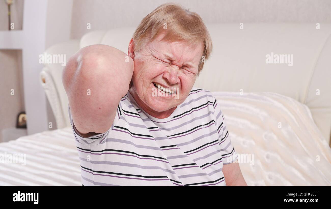 Donna anziana a letto con dolore al collo. Foto Stock