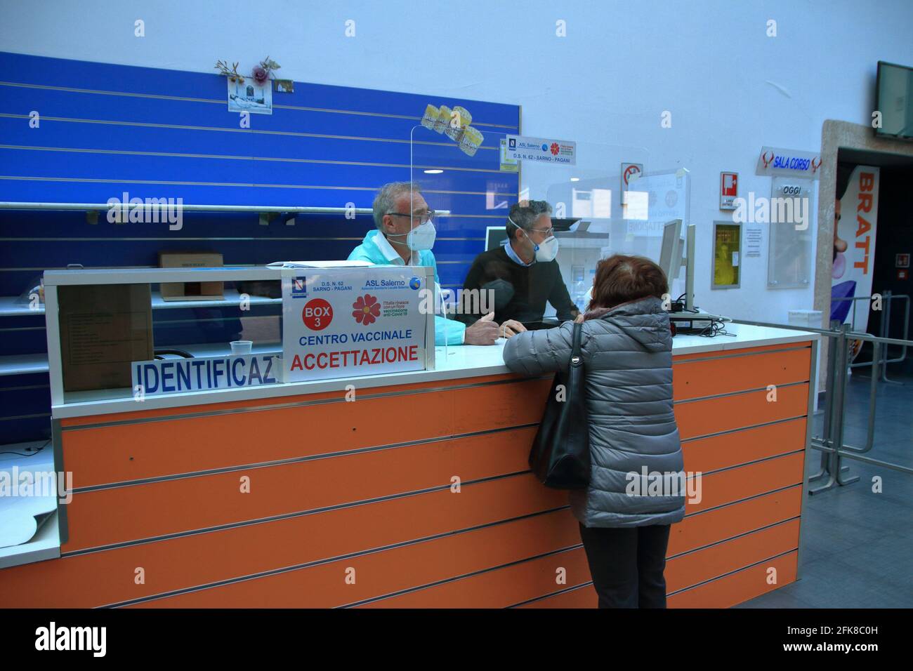 Persone che devono fare il vaccino contro il coronavirus presso i banchi del centro di vaccinazione per compilare la scheda di vaccinazione. Foto Stock
