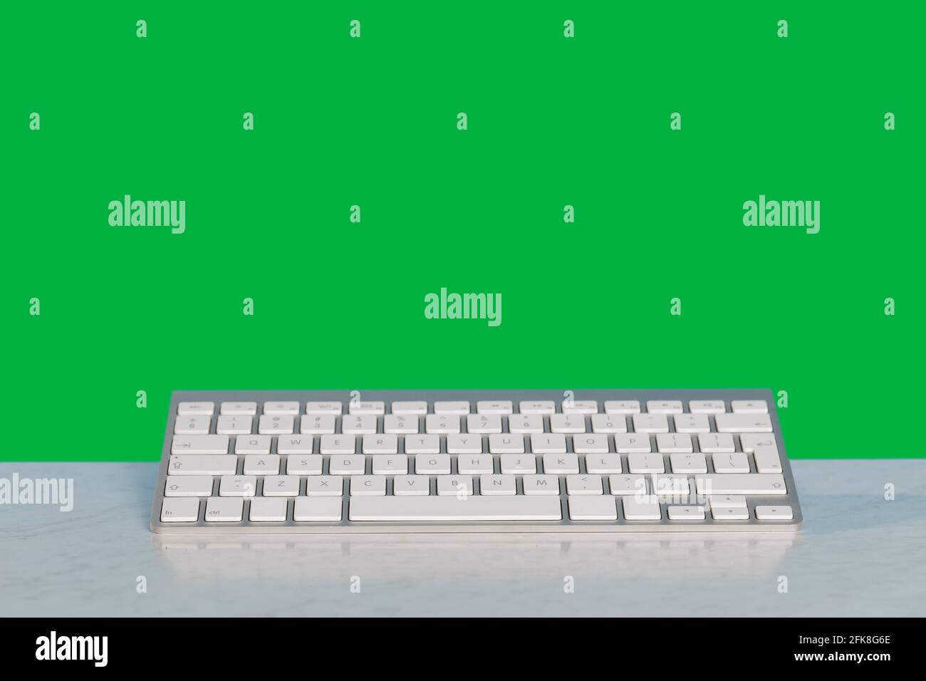 La tastiera di un computer si trova su una scrivania e sopra di essa si  trova uno sfondo verde pieno. Schermo verde Foto stock - Alamy