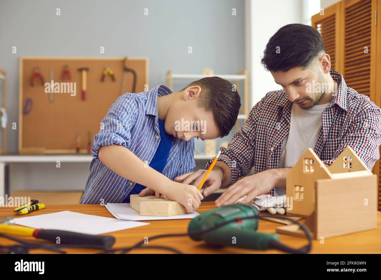 Padre e figlio che costruiscono la casa di uccelli in legno trascorrono il tempo insieme a. officina a casa Foto Stock