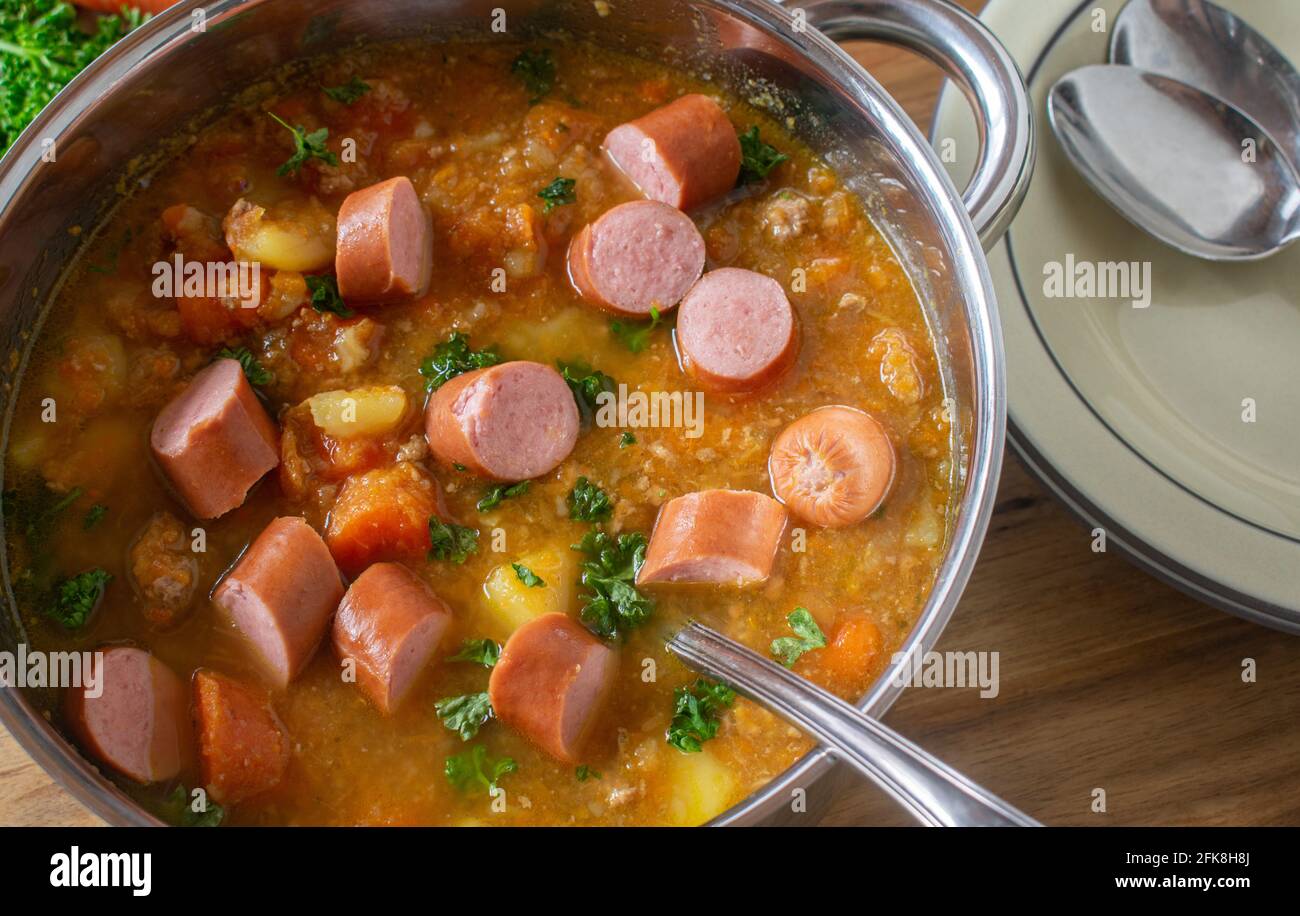 Vista dall'alto di una pentola con stufato di carote appena cucinato con patate, verdure di radice e salsicce bollite Foto Stock