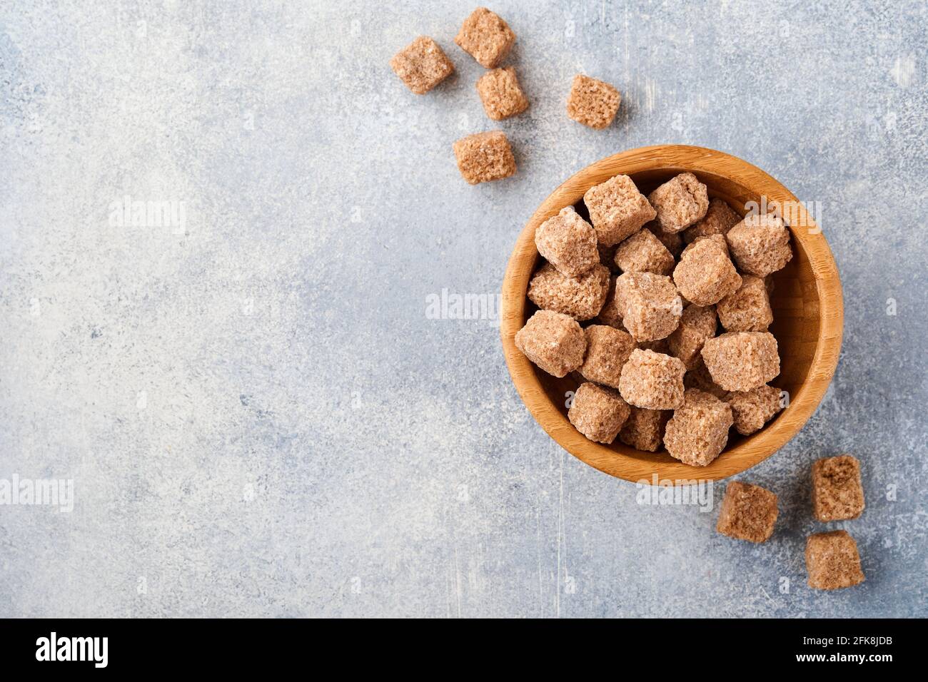 Canna zucchero cubo in bambù ciotola su sfondo grigio tavolo cemento. Vista dall'alto. Foto Stock