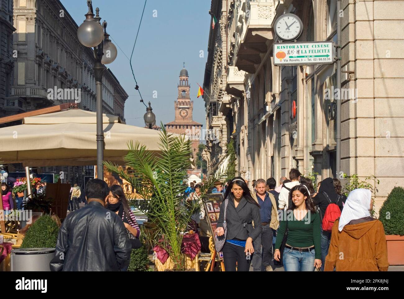 Pedoni in via Dante con il Castello Sforzesco Sullo sfondo Milano Lombardia Italia Foto Stock