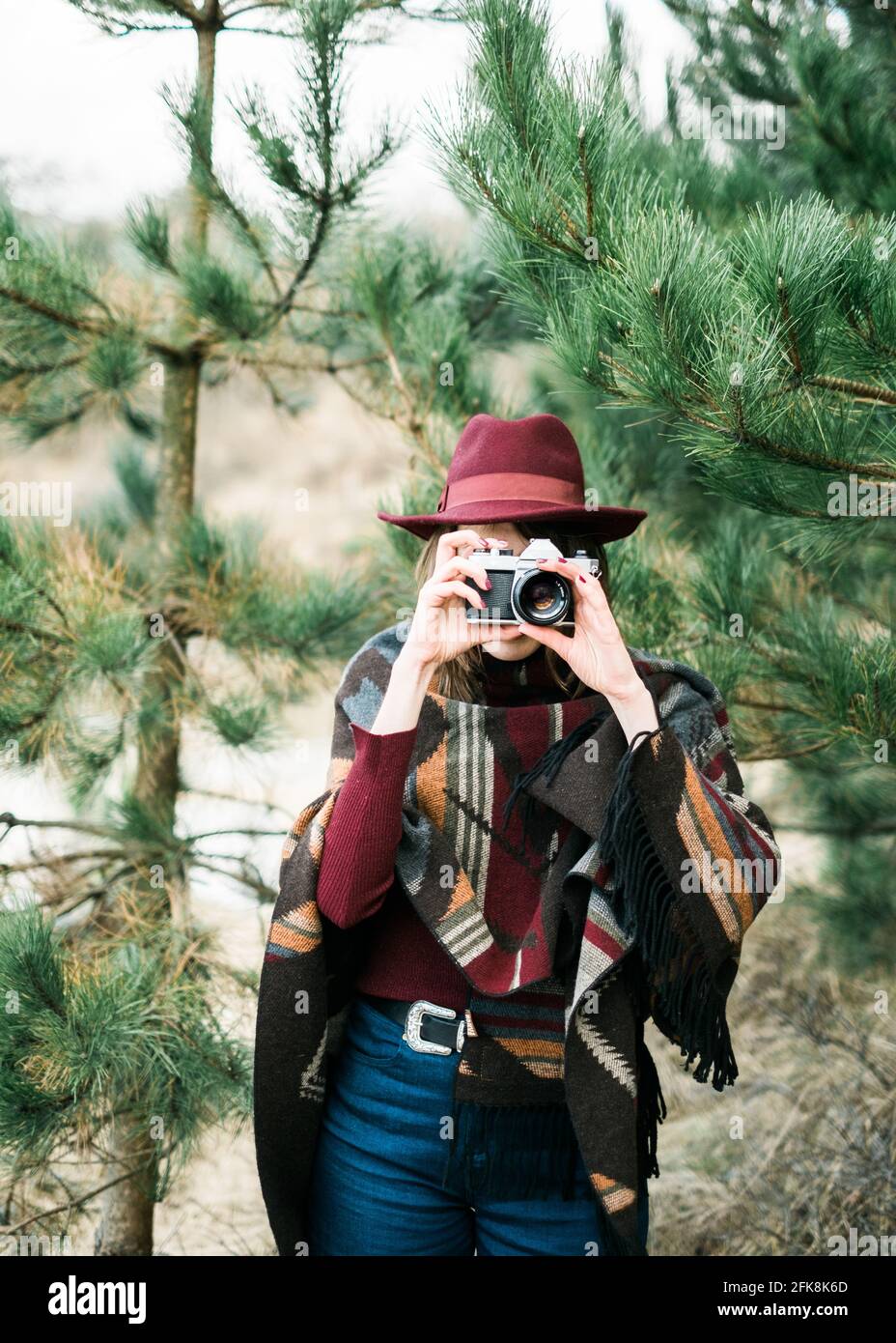 Giovane donna in una foresta in possesso di una fotocamera vintage. Kinfolk / stile all'aperto. Foto Stock