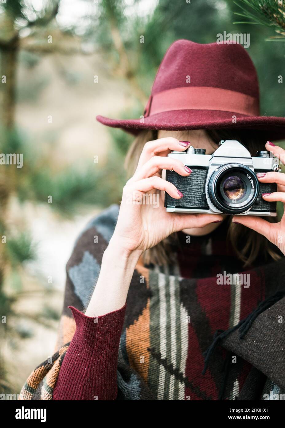 Giovane donna che fotografa in una foresta con una macchina fotografica d'epoca. Stile kinfolk/outdoor. Foto Stock