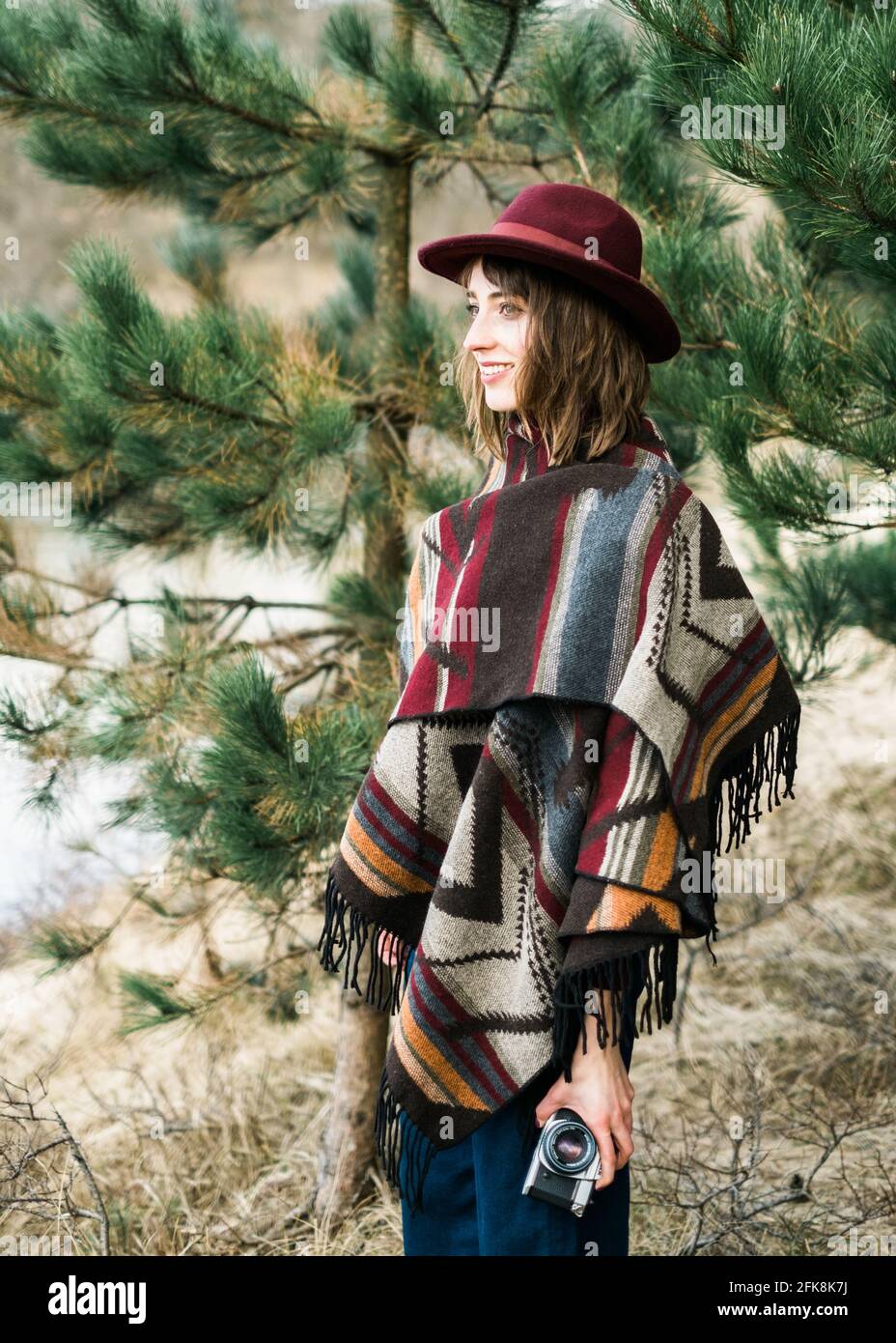 Giovane donna che fotografa in una foresta con una macchina fotografica d'epoca. Stile kinfolk/outdoor. Foto Stock