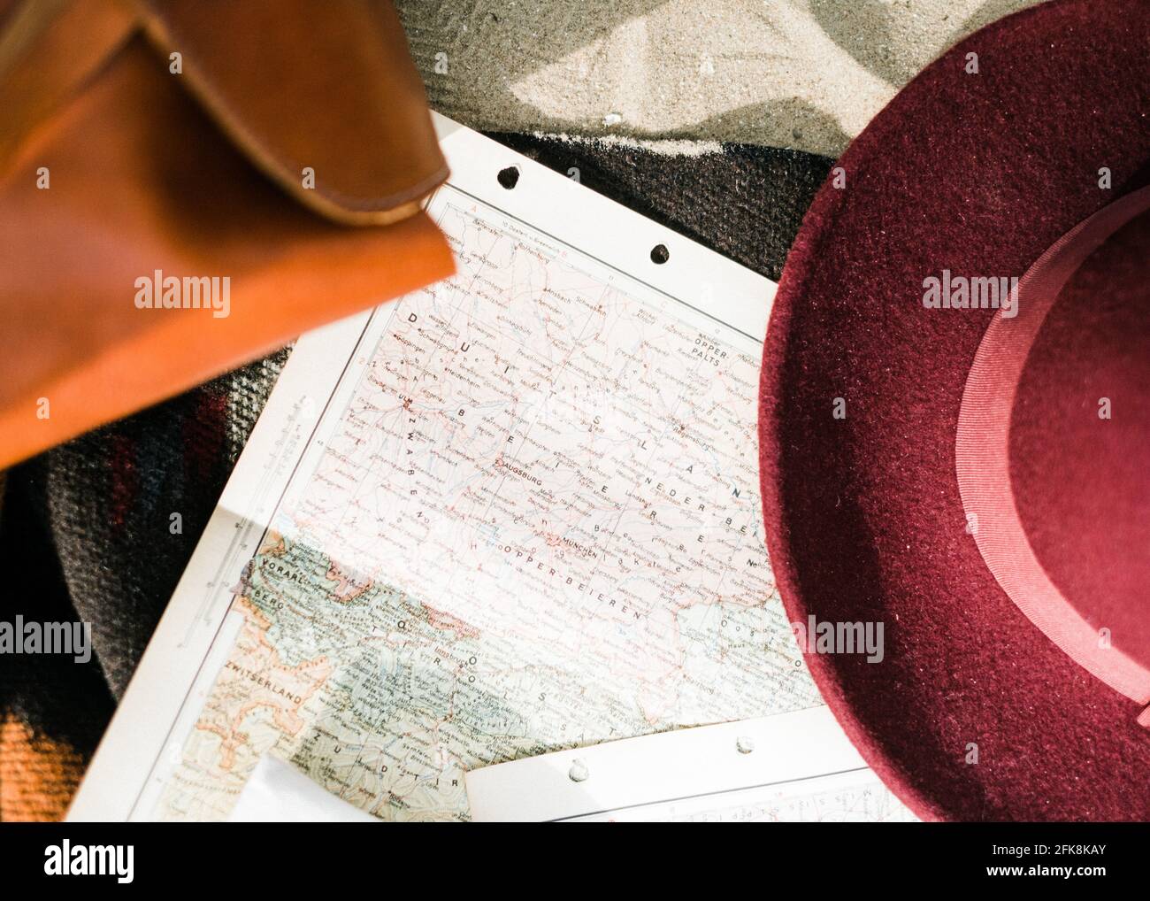 Ancora vita di cose da viaggio. Un passaporto, un cappello, una macchina fotografica e una mappa su una spiaggia Foto Stock