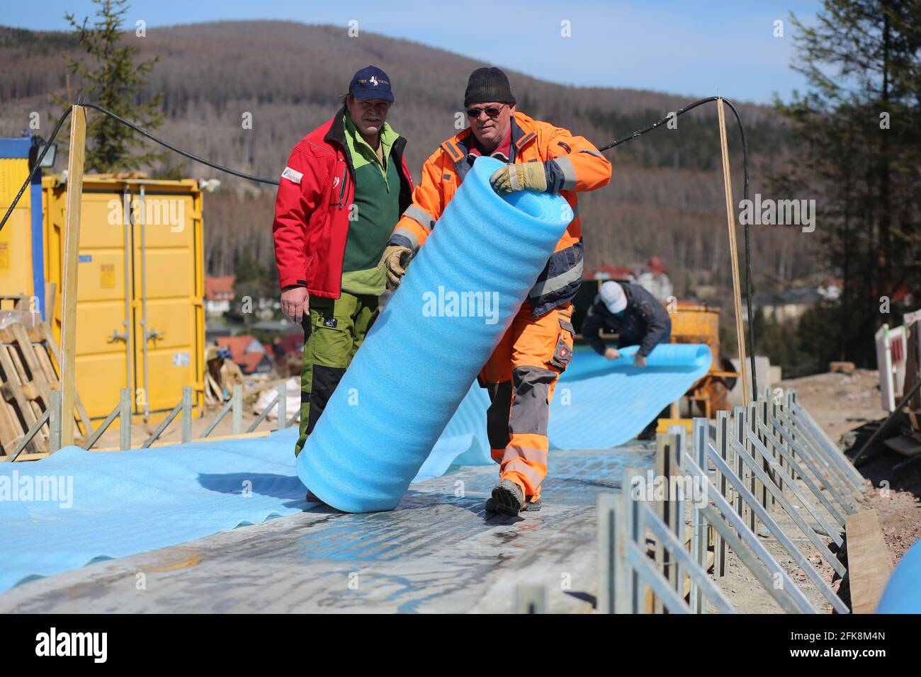 Schierke, Germania. 27 Apr 2021. Andreas Köhler (r) e Dirk Klaus, lavoratori edili dello Schierk Luge e del Bobsleigh Sports Club, si sono liberati in un cantiere per una nuova pista di slittino. Entro l'autunno 2021, un tracciato storico che esiste qui sotto il Brocken dal 1969 sarà ampiamente rinnovato. Circa 780000 euro saranno investiti nella pista da bob e slittino lunga 330 metri, che sarà poi utilizzata tutto l'anno. I bambini e i giovani potranno poi allenarsi di nuovo qui nelle condizioni più moderne. Credit: Fahren/dpa-Zentralbild/ZB/dpa/Alamy Live News Foto Stock