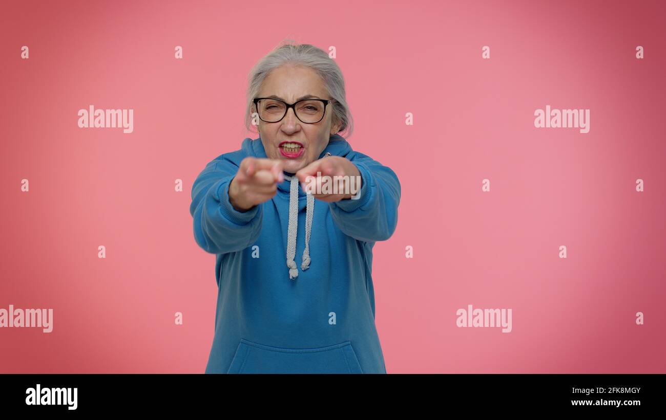 Donna anziana e grannia che punta intorno con il gesto della pistola delle dita, sparando uccidendo con la pistola delle mani Foto Stock