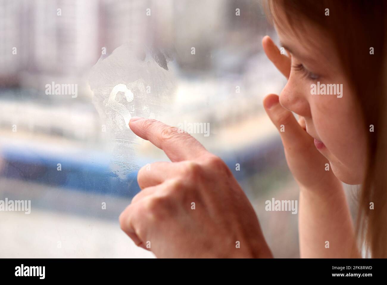 primo piano di una ragazza e una mano di un adulto attinge vetro della finestra Foto Stock