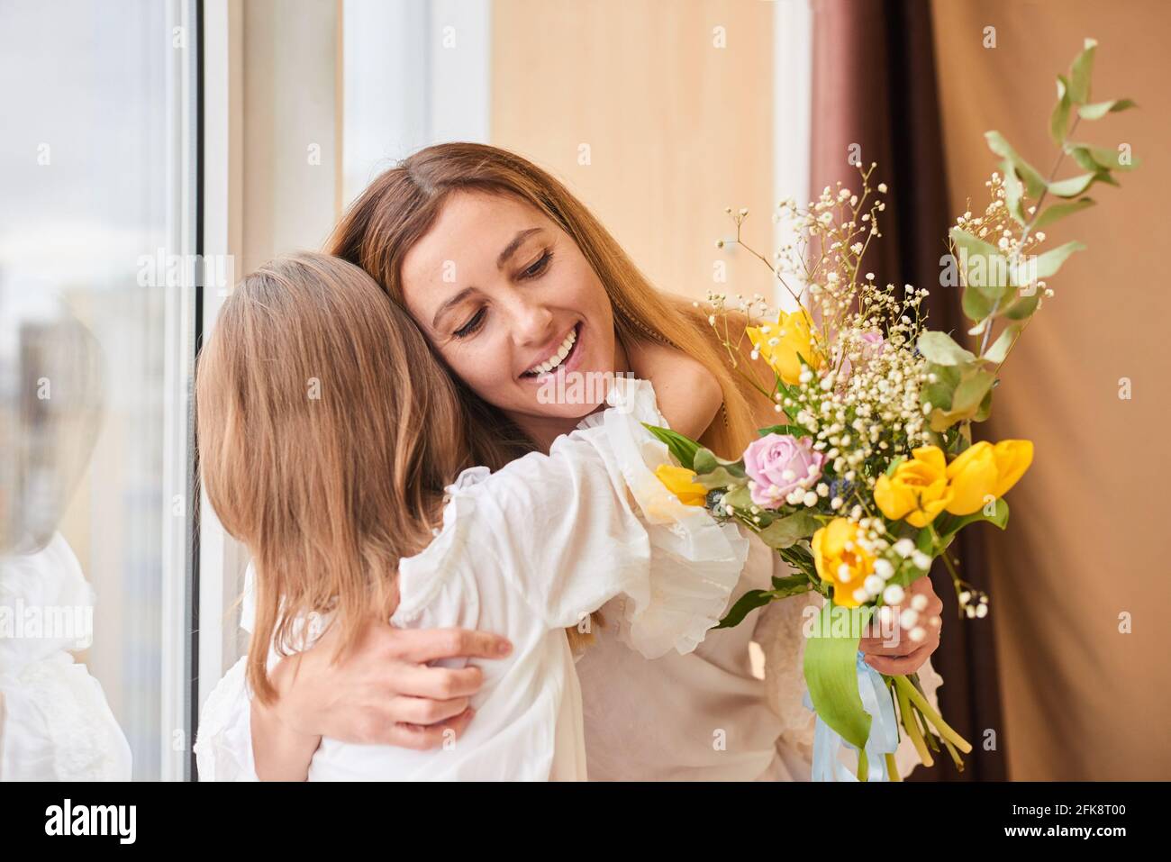 madre e figlia abbracciano fiori - famiglia, bambino, vacanza e festa concetto Foto Stock