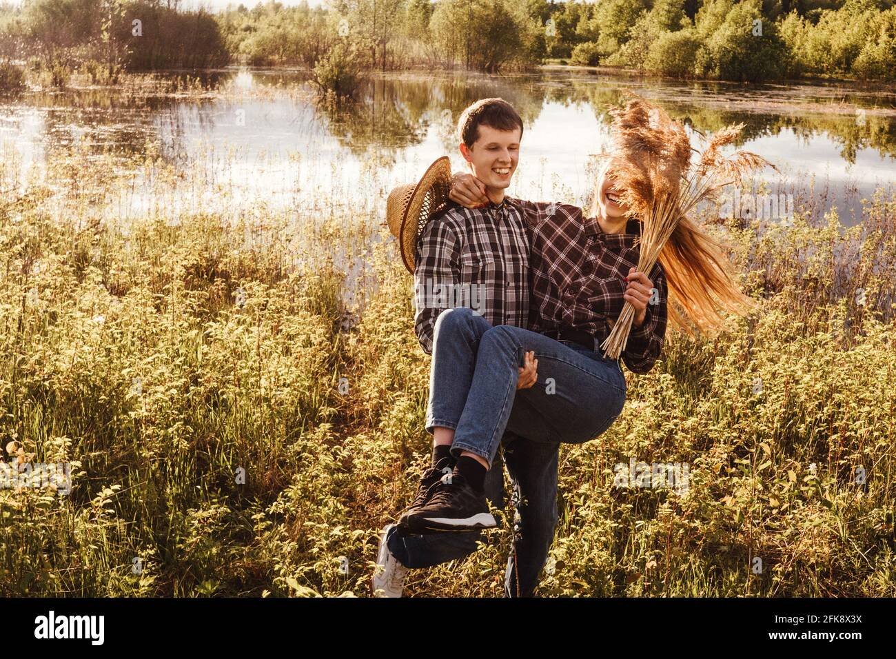 Una coppia innamorata nel campo. Donna che cavalcano un ragazzo, gioco divertente. Foto Stock