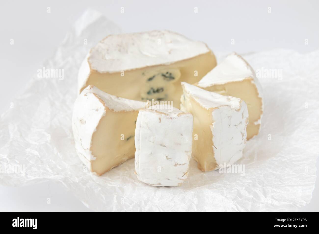 formaggio camembert o brie su sfondo bianco, formaggio su carta pergamena bianca, testa di formaggio a pezzi, formaggio francese Foto Stock