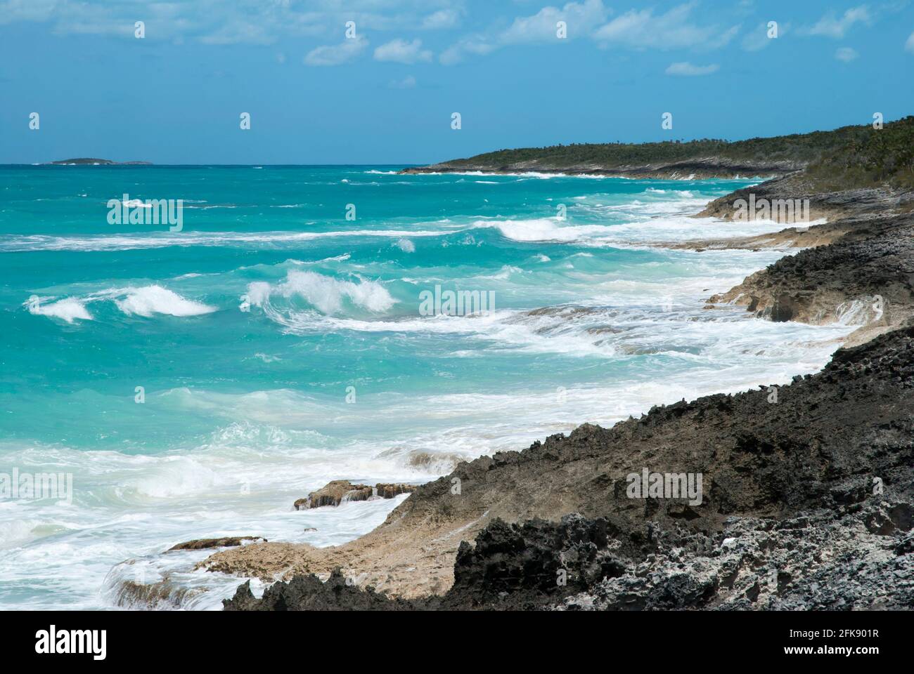 La vista delle onde di colore turchese che colpiscono la costa rocciosa sull'isola disabitata di Half Moon Cay (Bahamas). Foto Stock