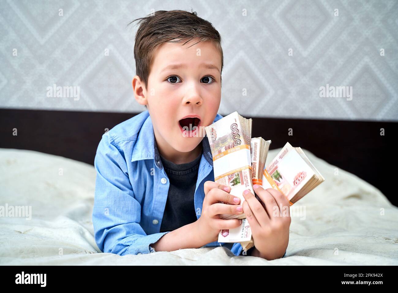 un ragazzino ha in mano banconote da cinque mila dollari ed è felice. Foto Stock