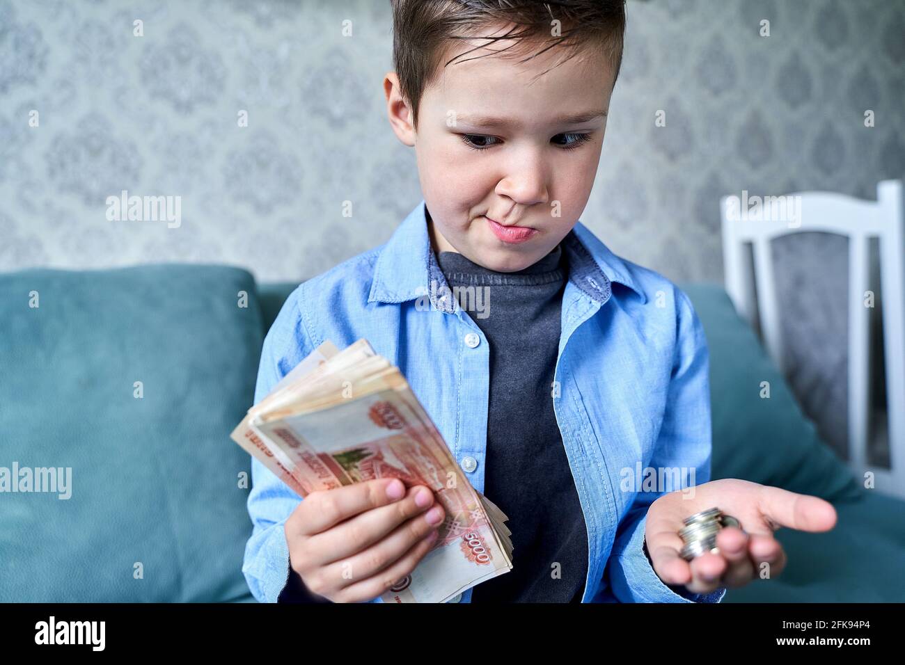 il bambino ha un sacco di soldi in una mano e piccole monete d'altra parte Foto Stock