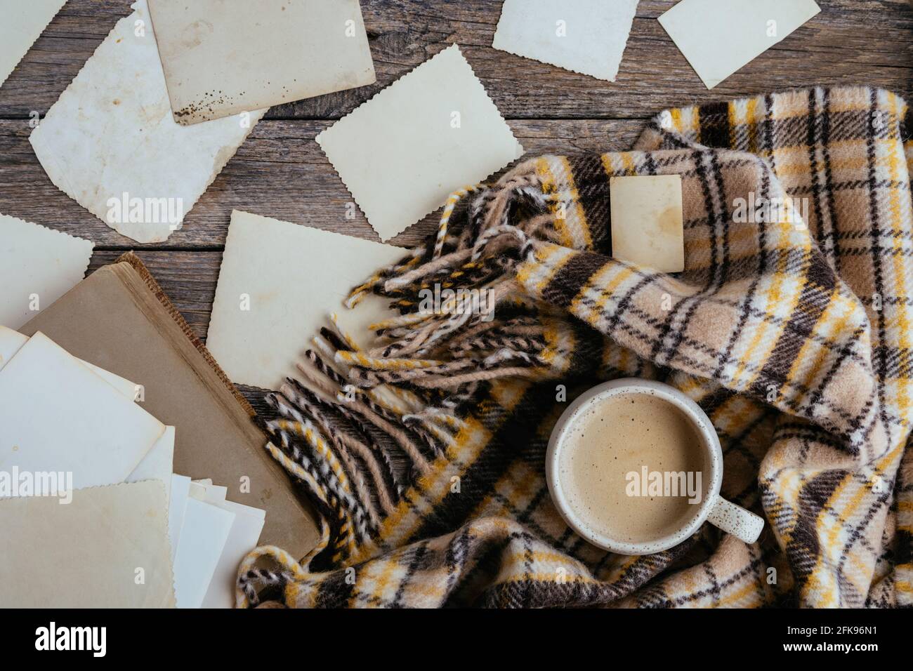 Cornici chiare vuote per posizionare le foto o il testo su sfondo di legno con tazza di caffè e bruno accogliente plaid. Composizione calda in stile retrò Foto Stock