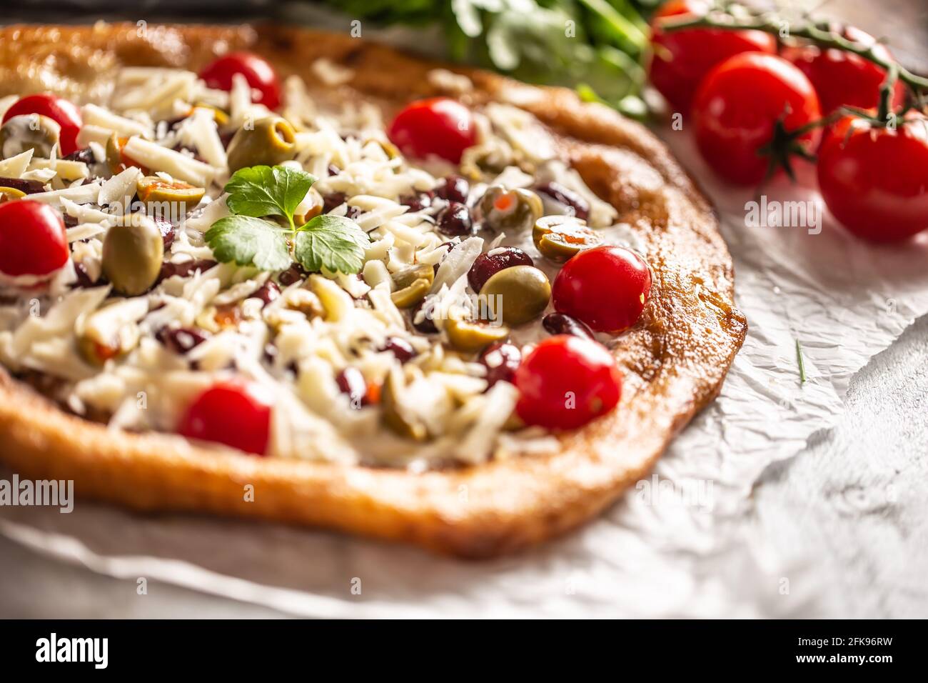 Langos gustosi e croccanti serviti perfettamente con pomodori ciliegini interi, formaggio gratinato, fagioli e olive verdi greche. Foto Stock