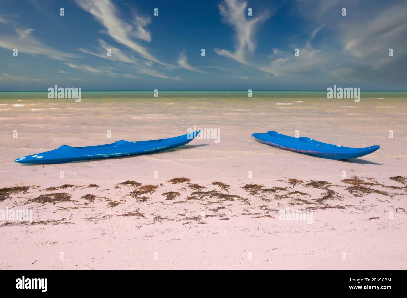 Due kaiak su una spiaggia tropicale deserta sull'isola di Holbox in Messico. Sullo sfondo il mare caraibico e il cielo parzialmente nuvoloso. Luogo ideale per Foto Stock