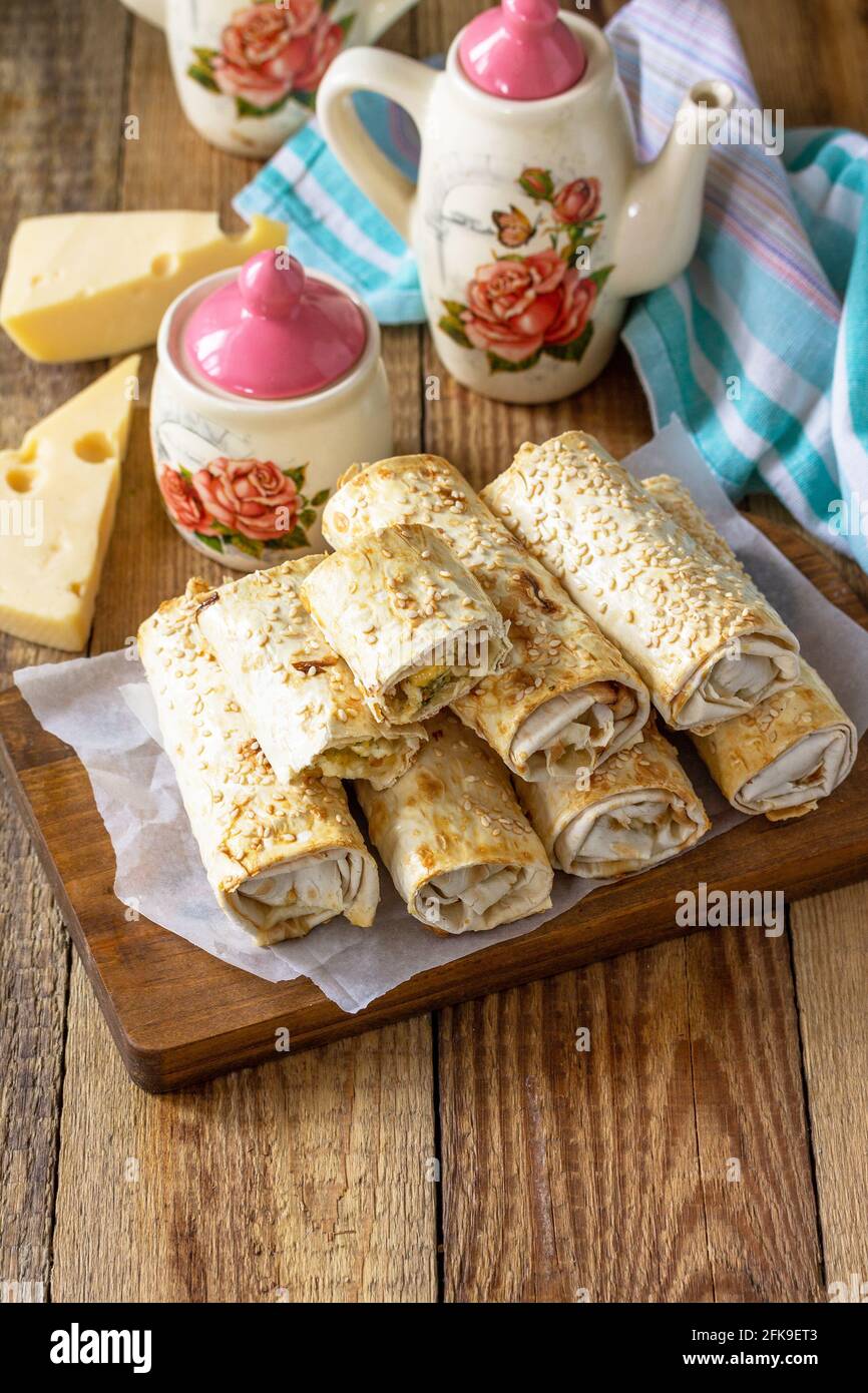 Colazione, picnic, pranzo o snack. Rotolo di lavasch con formaggio di cottage, formaggio e spinaci su un tavolo rustico. Spazio di copia. Foto Stock