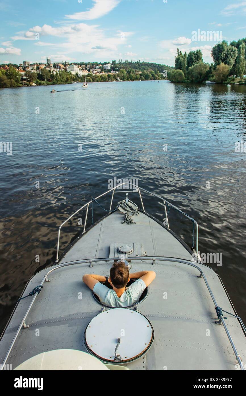 Felice giovane uomo che si rilassa in barca che galleggia in acque tranquille del fiume. Buona giornata estiva soleggiata in natura. Concept vacanza sul Lake.Man godendo di vista del paesaggio Foto Stock