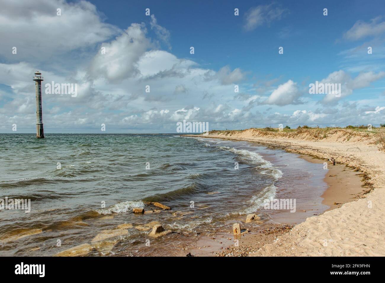 Giorno estivo soleggiato dal Mar Baltico.Wandelust viaggio background.Power di acqua energia passing.Amazing vista del mare freddo con vecchio faro, le onde e ciottoli Foto Stock
