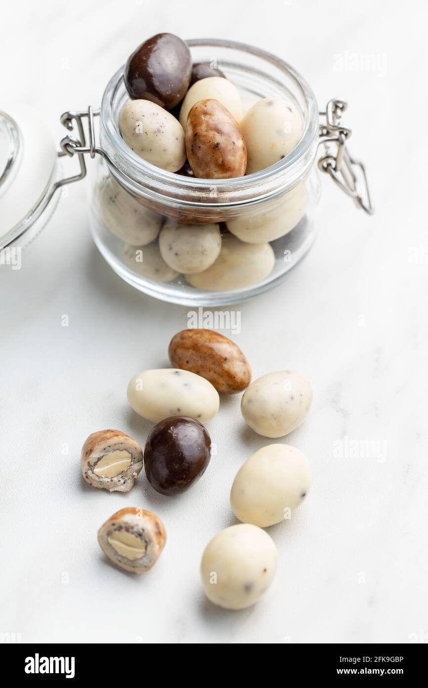 Mandorle dolci al cioccolato. Uova di cioccolato in vaso su tavola bianca. Foto Stock
