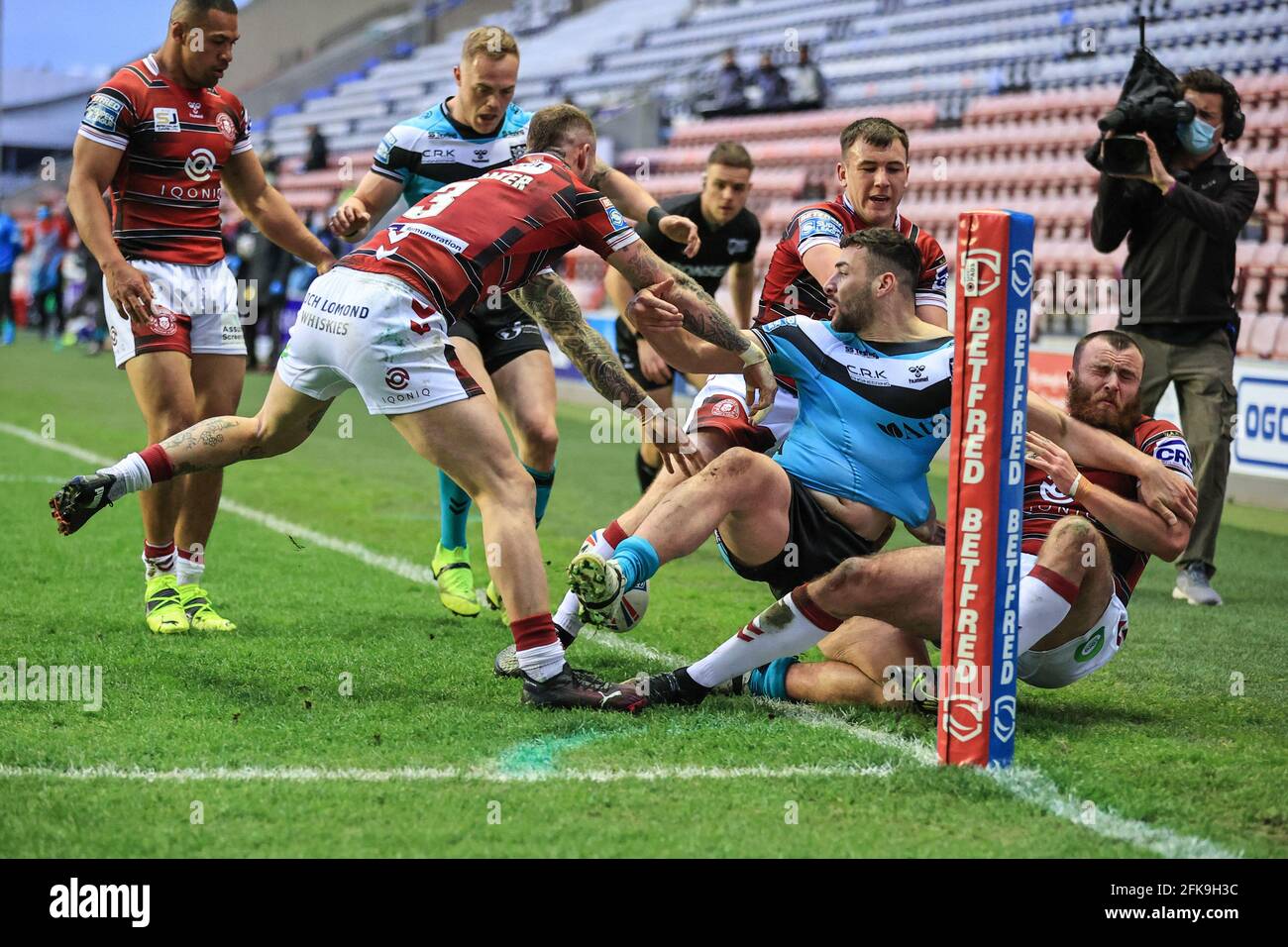 Jake Bibby (22) di Wigan Warriors tira Jake Connor (1) Di Hull FC fuori gioco come lui fa un trattino per la linea di prova a destra nell'angolo Foto Stock