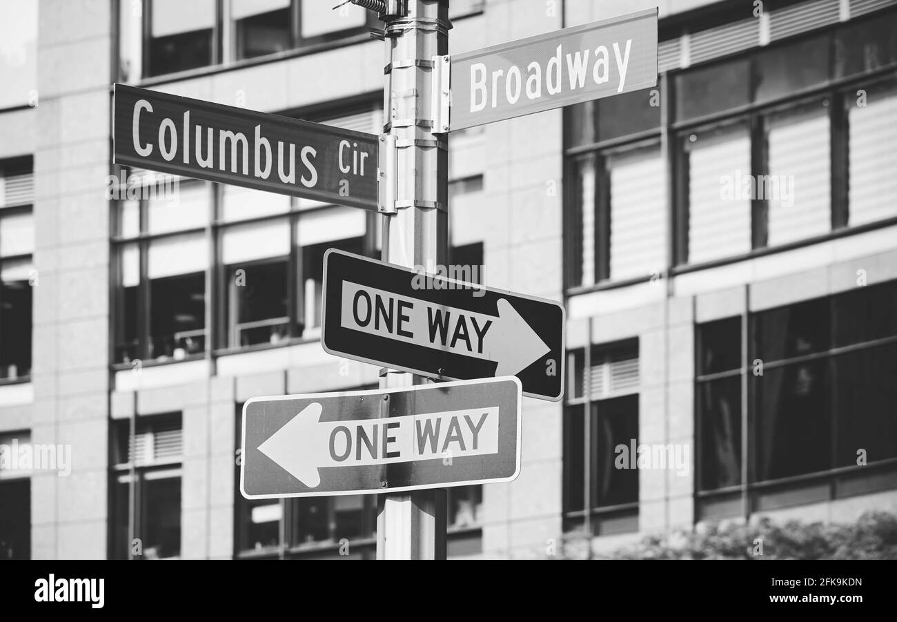 Immagine in bianco e nero di un post con Columbus Circle, Broadway e cartelli stradali a senso unico, fuoco selettivo, New York City, USA. Foto Stock