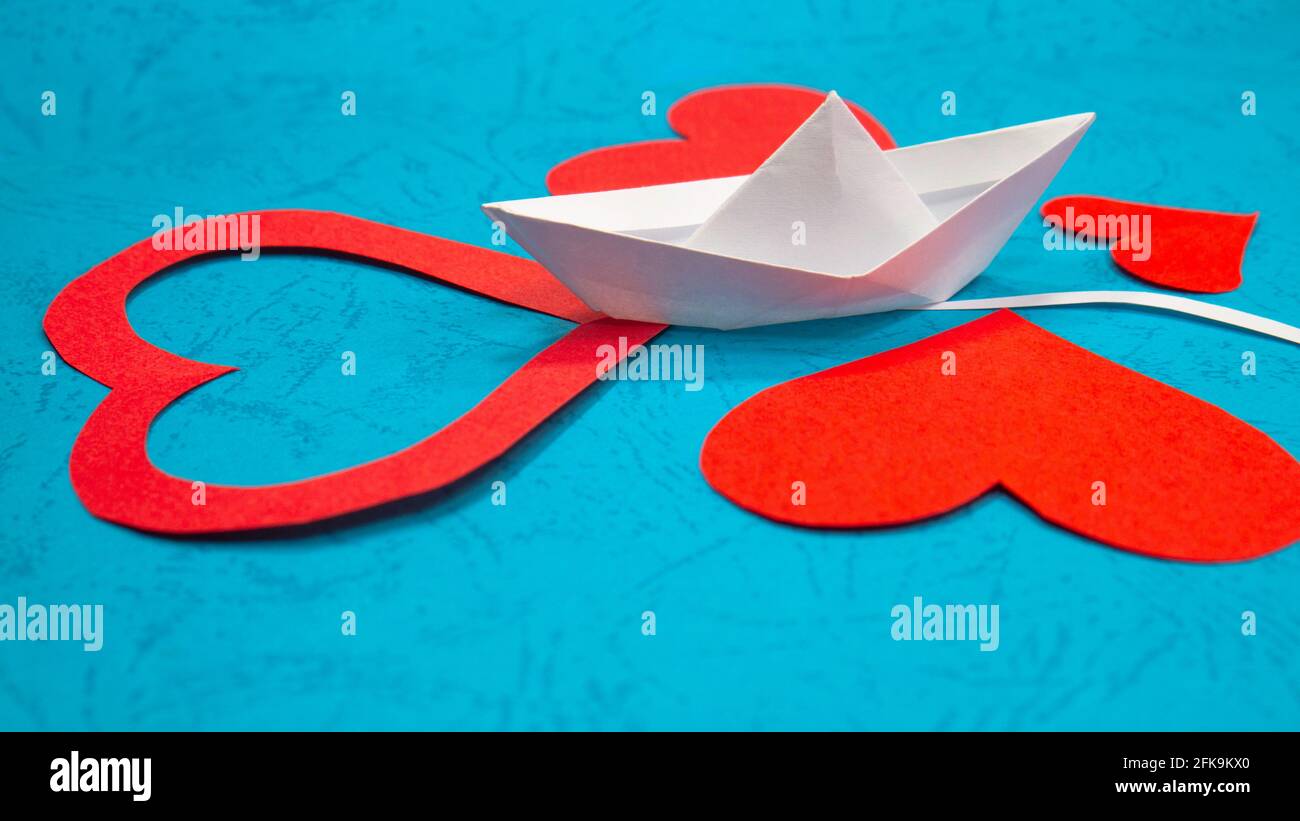 Una nave di carta origami veleggia attraverso i cuori rossi. Una metafora  per trovare l'amore nella vita. Amore per la vela Foto stock - Alamy