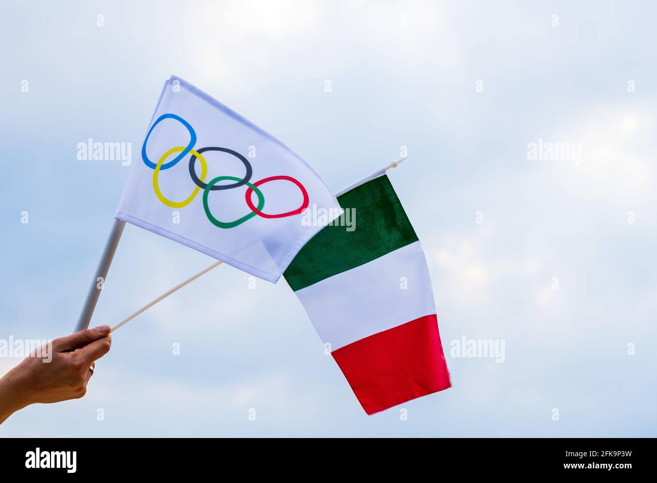 Fan che sventola la bandiera nazionale dell'Italia e la bandiera olimpica con anelli simbolo delle olimpiadi. Foto Stock