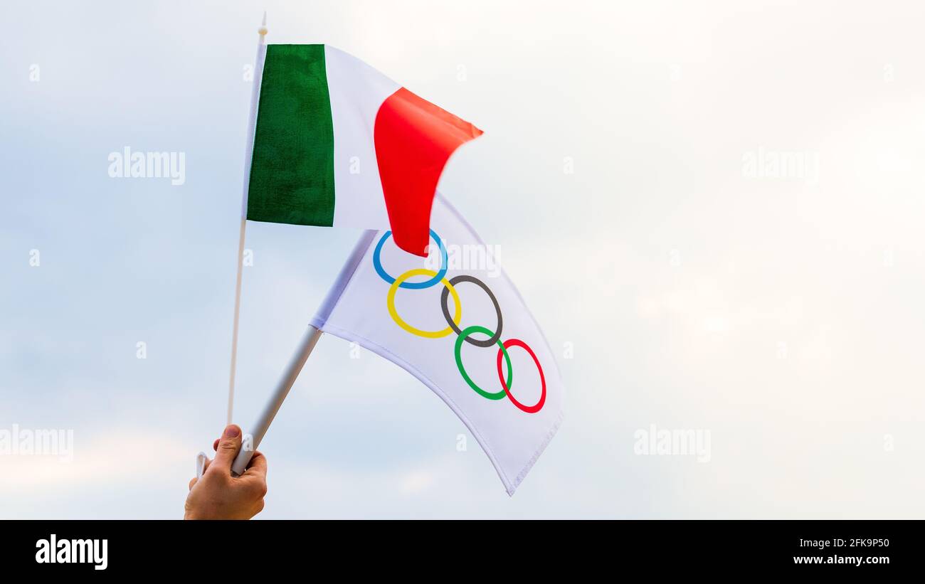 Fan che sventola la bandiera nazionale dell'Italia e la bandiera olimpica con anelli simbolo delle olimpiadi. Foto Stock