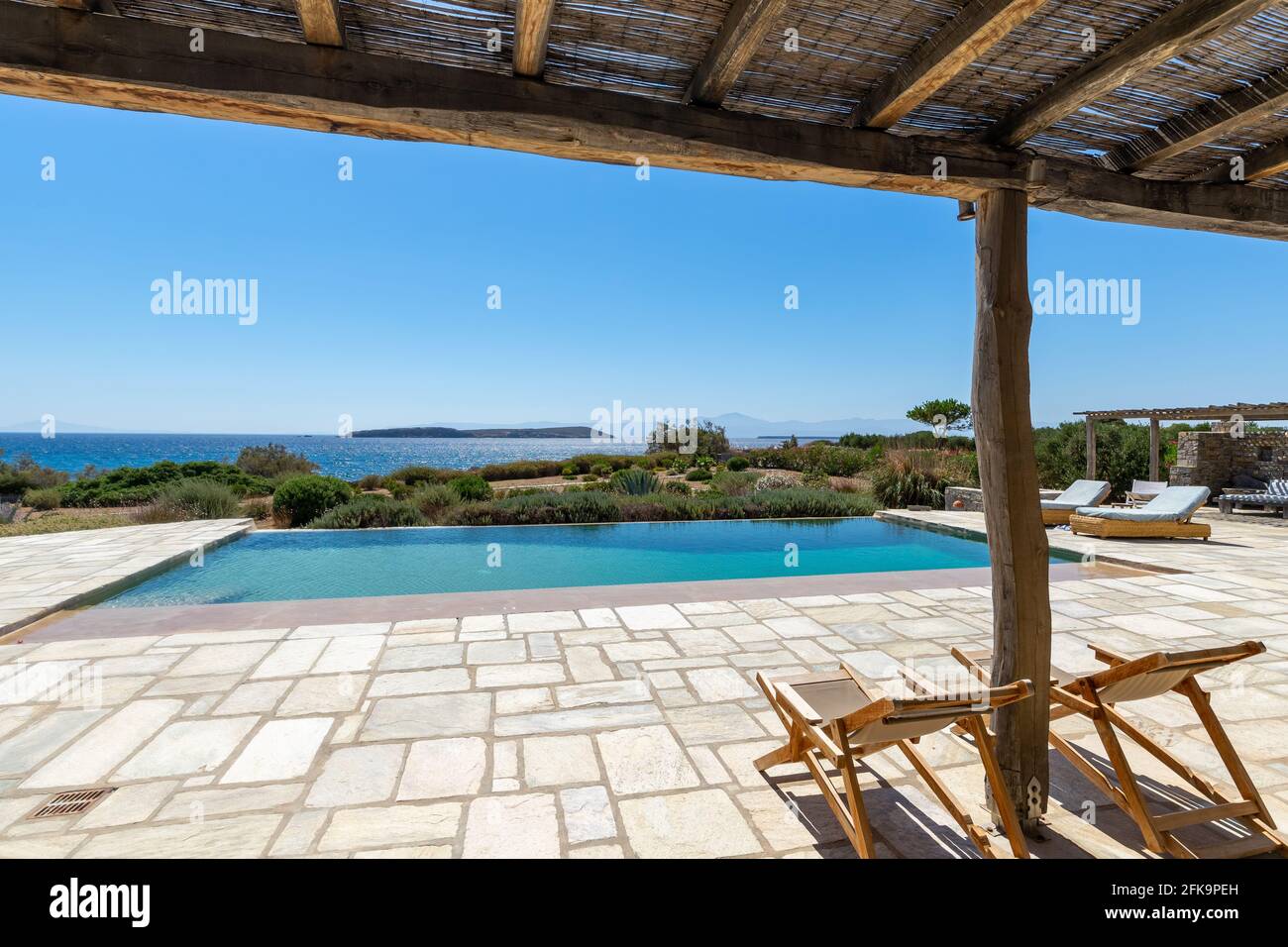 accoglienti lettini sulla terrazza con giardino mediterraneo e piscina vicino al mare. Foto Stock