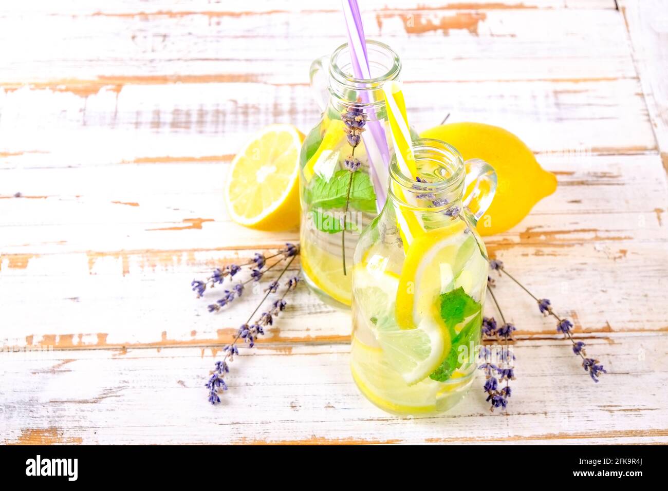 Limonata ghiacciata di lavanda, limone, paglia. Due classiche bevande vergini mojito, cocktail analcolico con ghiaccio in due bottiglie d'hipster d'epoca, gruntate Foto Stock