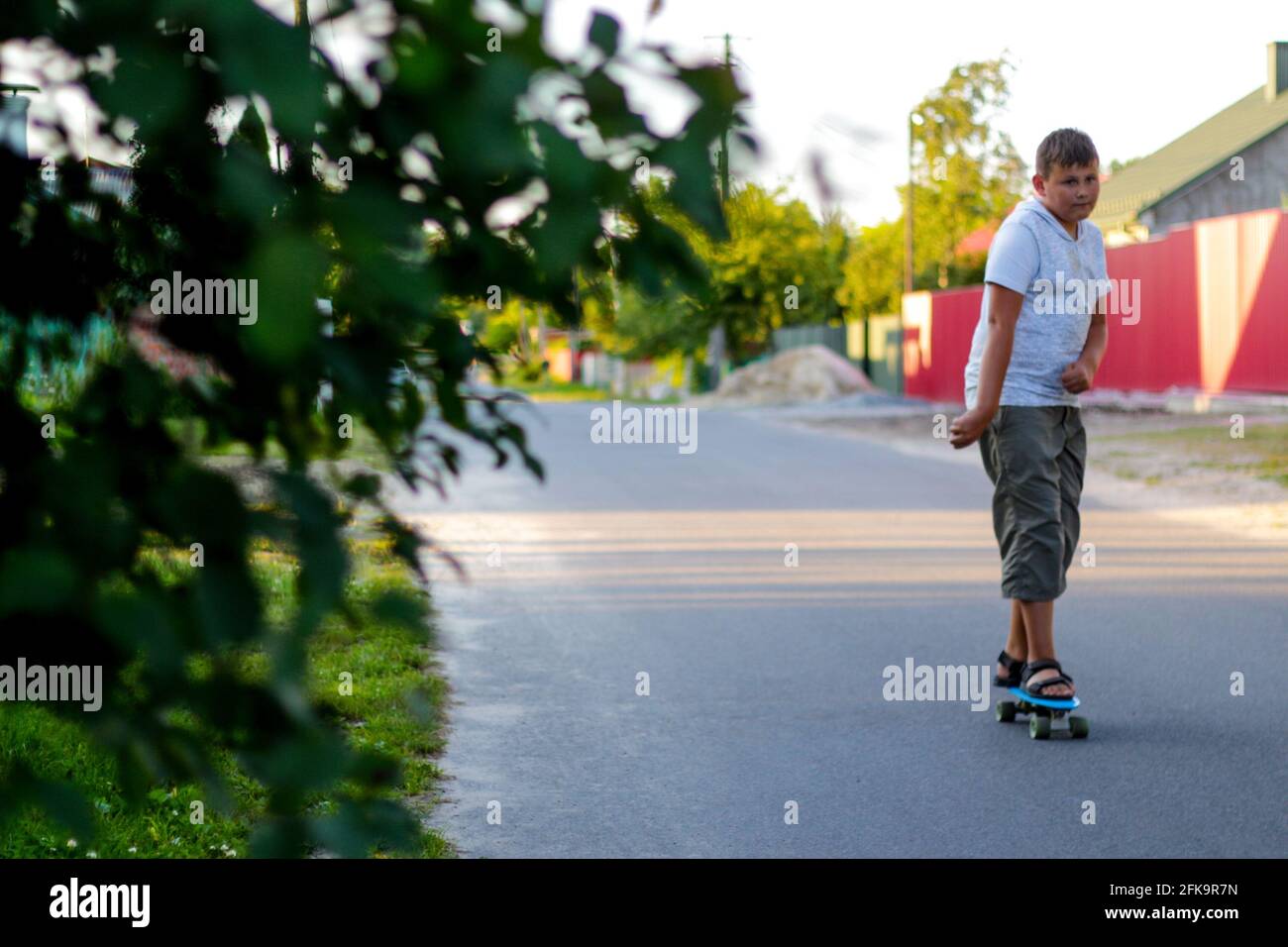 Sfida il ragazzo teenager a giocare sullo skateboard in strada. Caucasico bambino equitazione penny board, pratica skateboard. Concetto di sport attivo infantile. Sfocatura Foto Stock