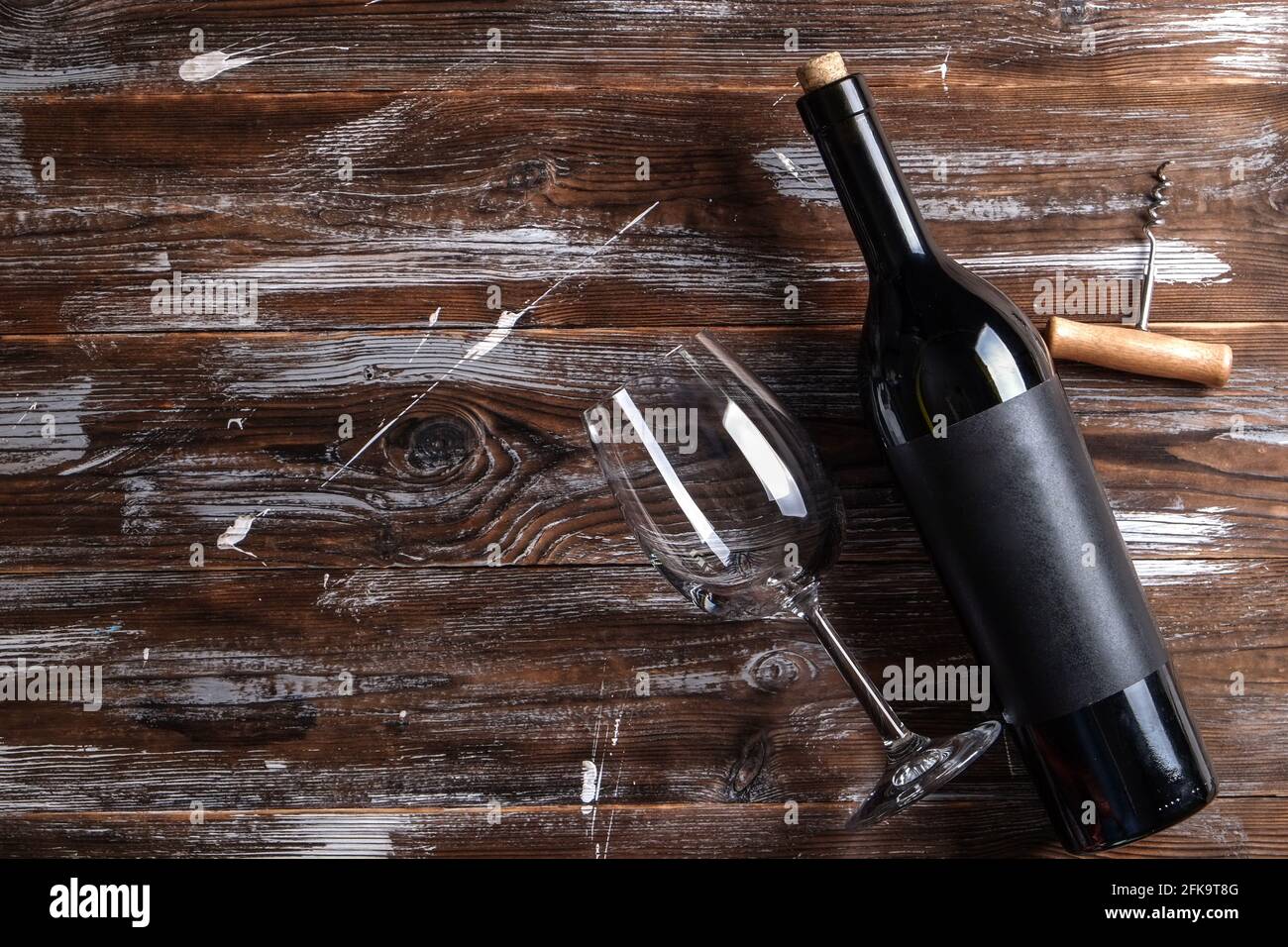 Bottiglia di vino rosso d'epoca con etichetta nera opaca vuota, cavatappi su sfondo di tavola in legno grintato. Bottiglia costosa di cabernet sauvignon Concept. Foto Stock