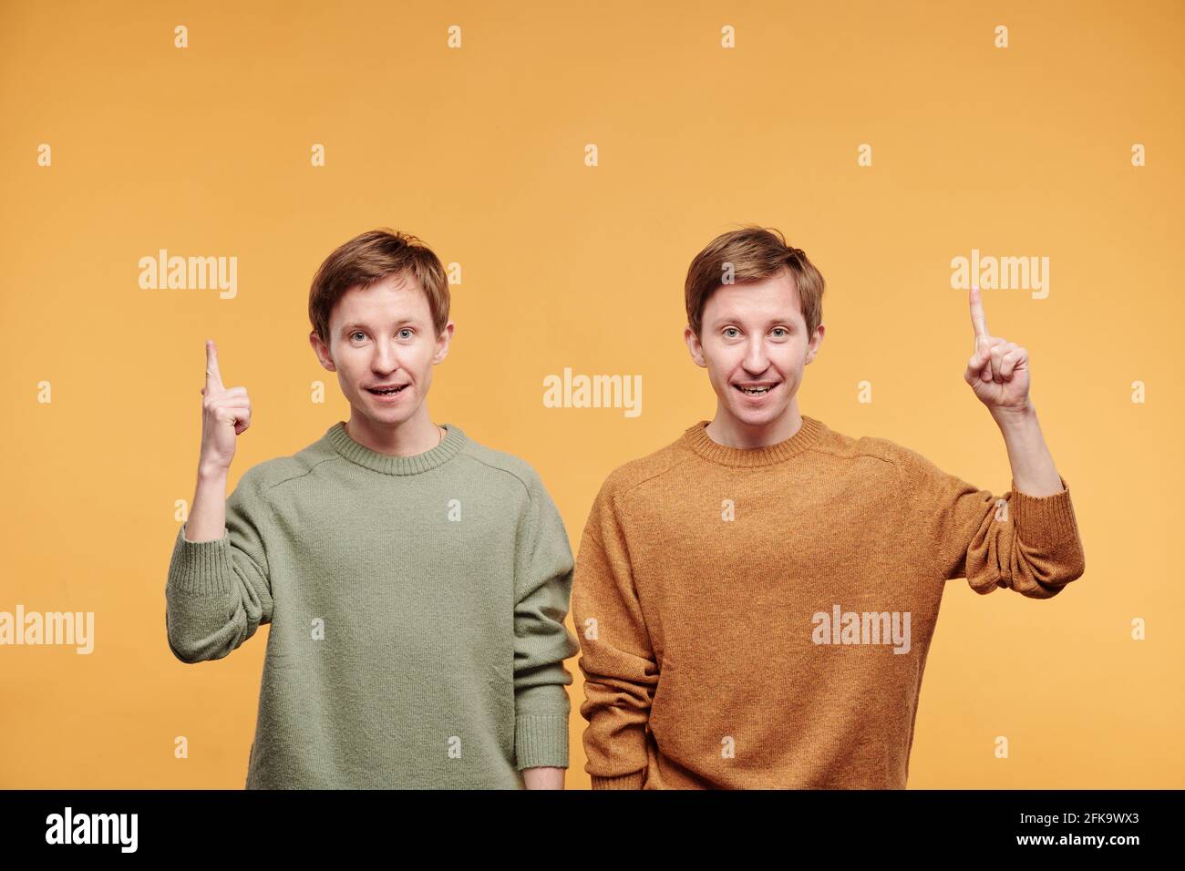 Ritratto di giovani fratelli gemelli con capelli rossi di ispirazione allegra mostrare le dita dell'indice verso l'alto mentre si ha un'idea brillante Foto Stock