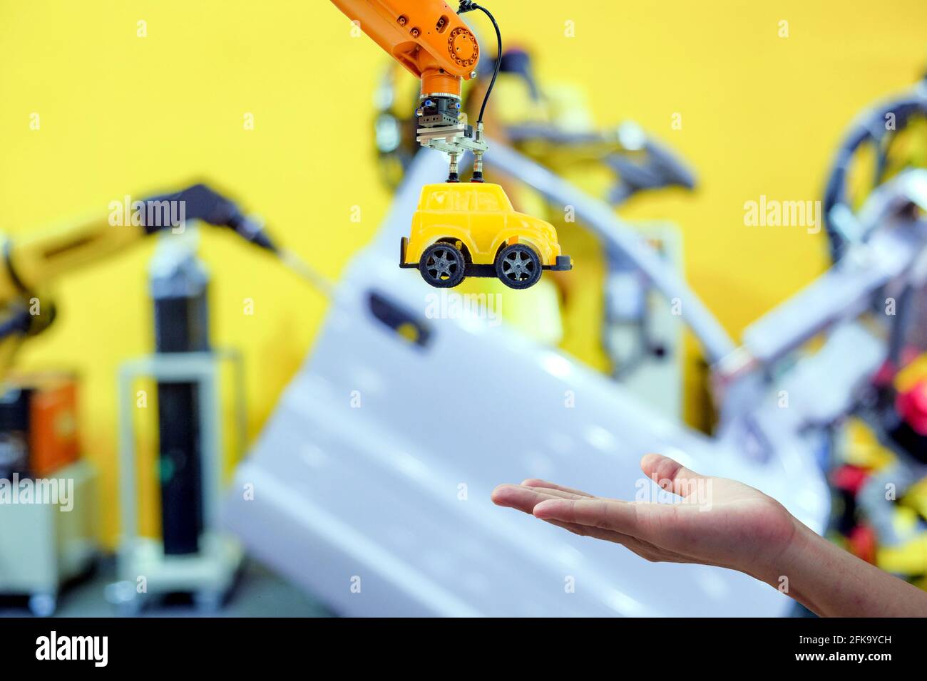 Primo piano industriale robotica che afferra il giocattolo giallo inviare a mano umano su sfondo sfocato Smart Factory, industria 4.0 e tecnologia iot concepะ Foto Stock