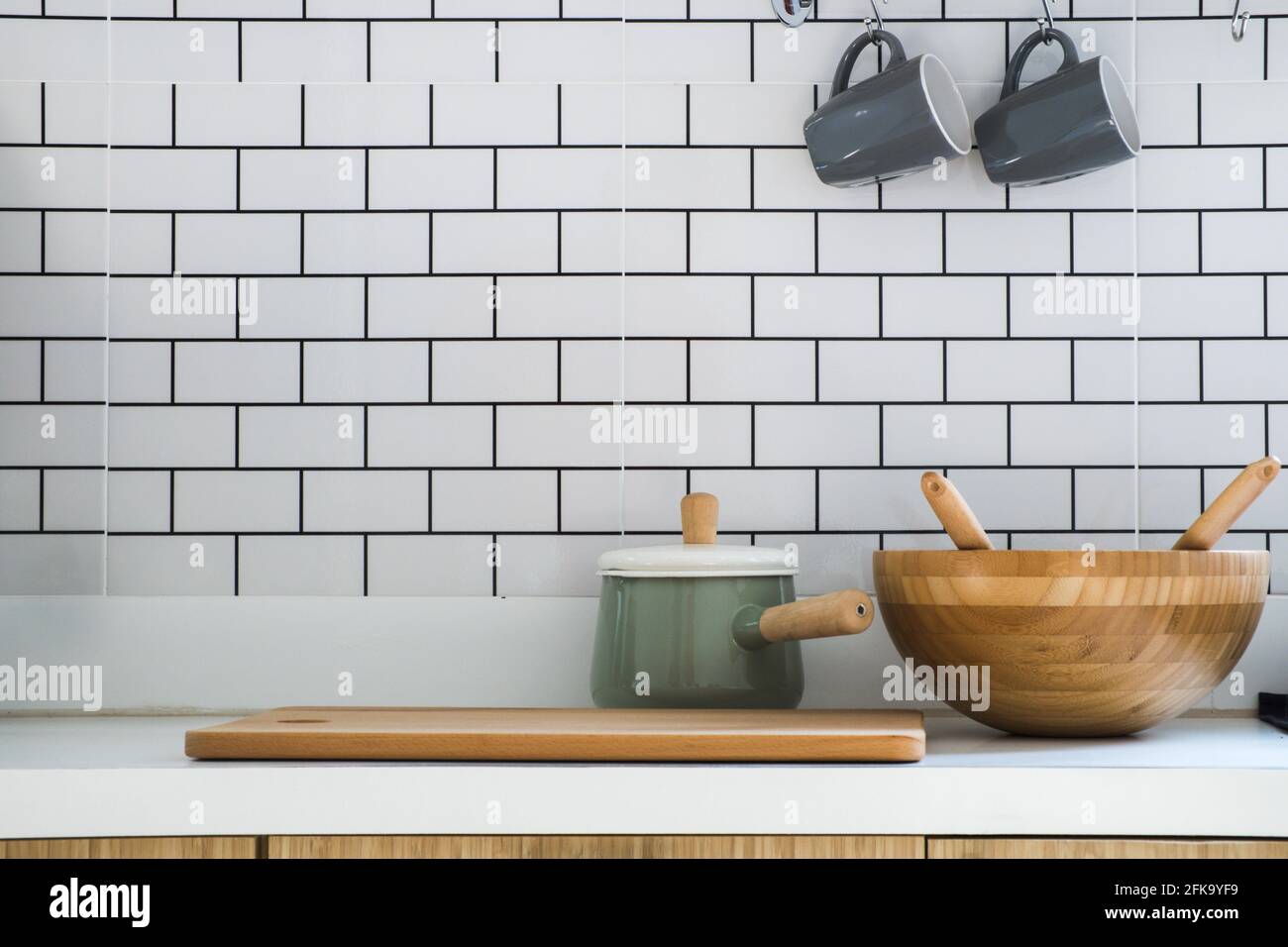 Primo piano cucina con pentola, tritare legno, vasca in legno e due tazze da caffè in ceramica messo su banco moderno, interni e arredamento di casa in stile moderno Foto Stock