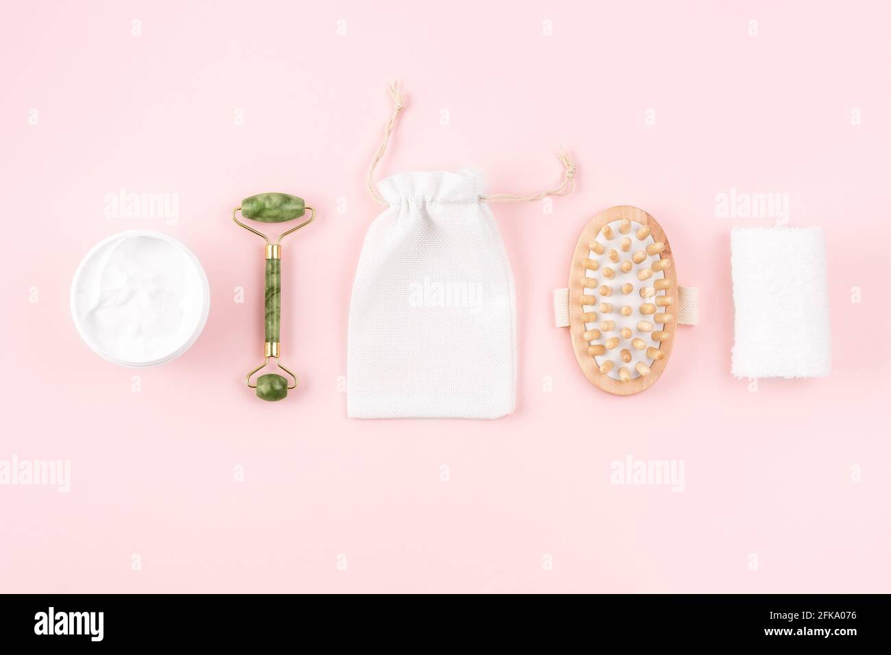 Set benessere, asciugamani, spazzola massaggiante, crema corpo, rullo in marmo su superficie rosa. Concetto eco zero rifiuti. Foto Stock