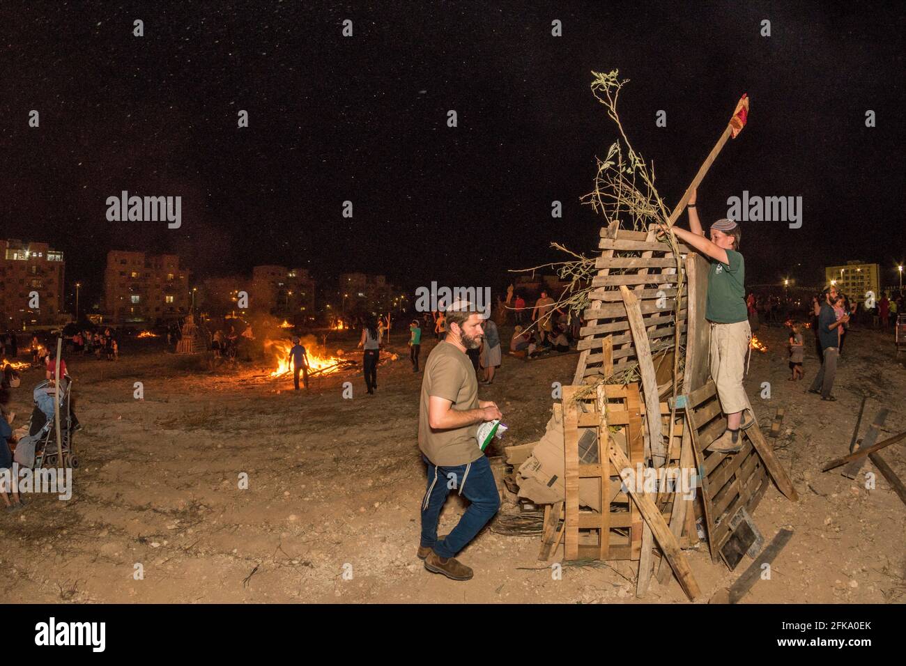 Persone che fanno fuoco durante la festa ebraica di Lag Ba'Omer, che si svolge ogni 18 del mese ebraico Iyar. È consuetudine durante questa vacanza fare incendi. Quest'anno, a causa del pericolo di incendio, tutti gli incendi sono stati concentrati in pochi siti, da cui il gran numero di piri. Foto Stock