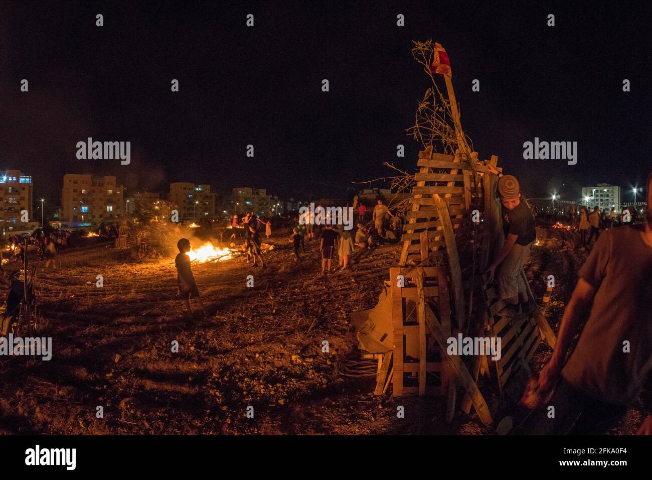 Persone che fanno fuoco durante la festa ebraica di Lag Ba'Omer, che si svolge ogni 18 del mese ebraico Iyar. È consuetudine durante questa vacanza fare incendi. Quest'anno, a causa del pericolo di incendio, tutti gli incendi sono stati concentrati in pochi siti, da cui il gran numero di piri. Foto Stock