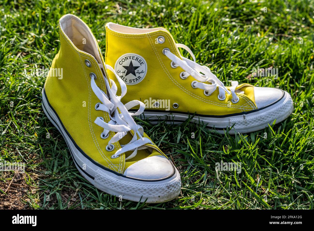 Sneakers All-Star di Yellow Chuck Taylor Converse su erba verde in molla Foto Stock