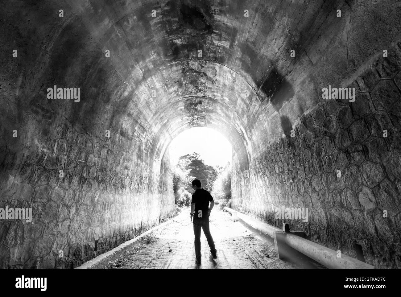 Silhouette turistico esplorato nell'antico tunnel ferroviario, abbandonato 19 ° secolo architettura ad oggi vicino a da Lat, Vietnam Foto Stock