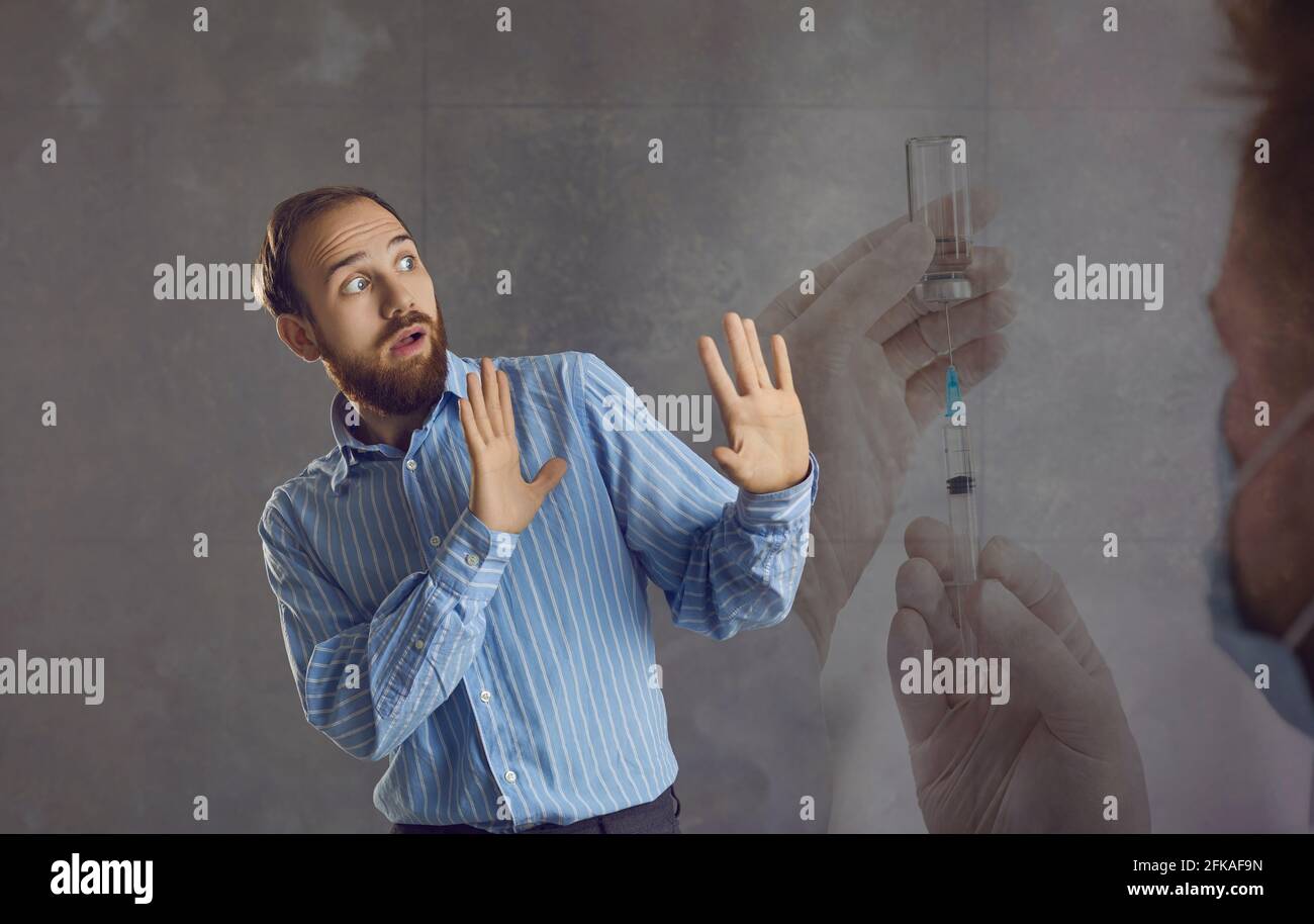 L'uomo adulto ondeggia le braccia, sentendo grande timore di essere iniettato con il vaccino contro Covid-19. Foto Stock
