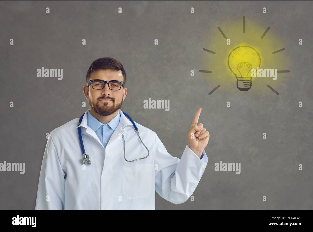 Ritratto di un medico orgoglioso che indica la lampadina come simbolo di idee e soluzioni innovative Foto Stock