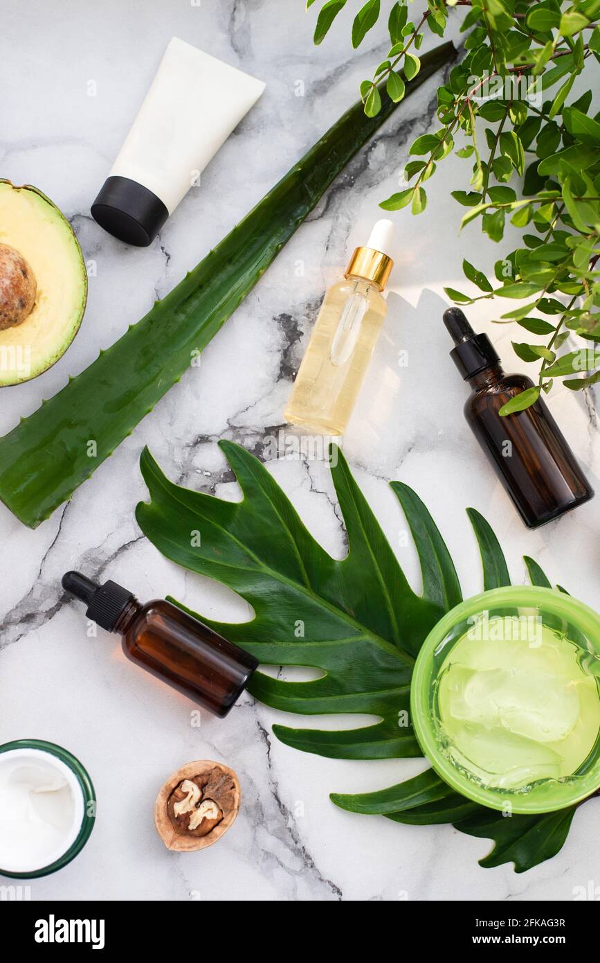 Una bella composizione con olio, sapone, avocado e noci. Bottiglie con prodotti cosmetici spa su sfondo a foglia di palma, vista dall'alto. Salone di bellezza procedu Foto Stock