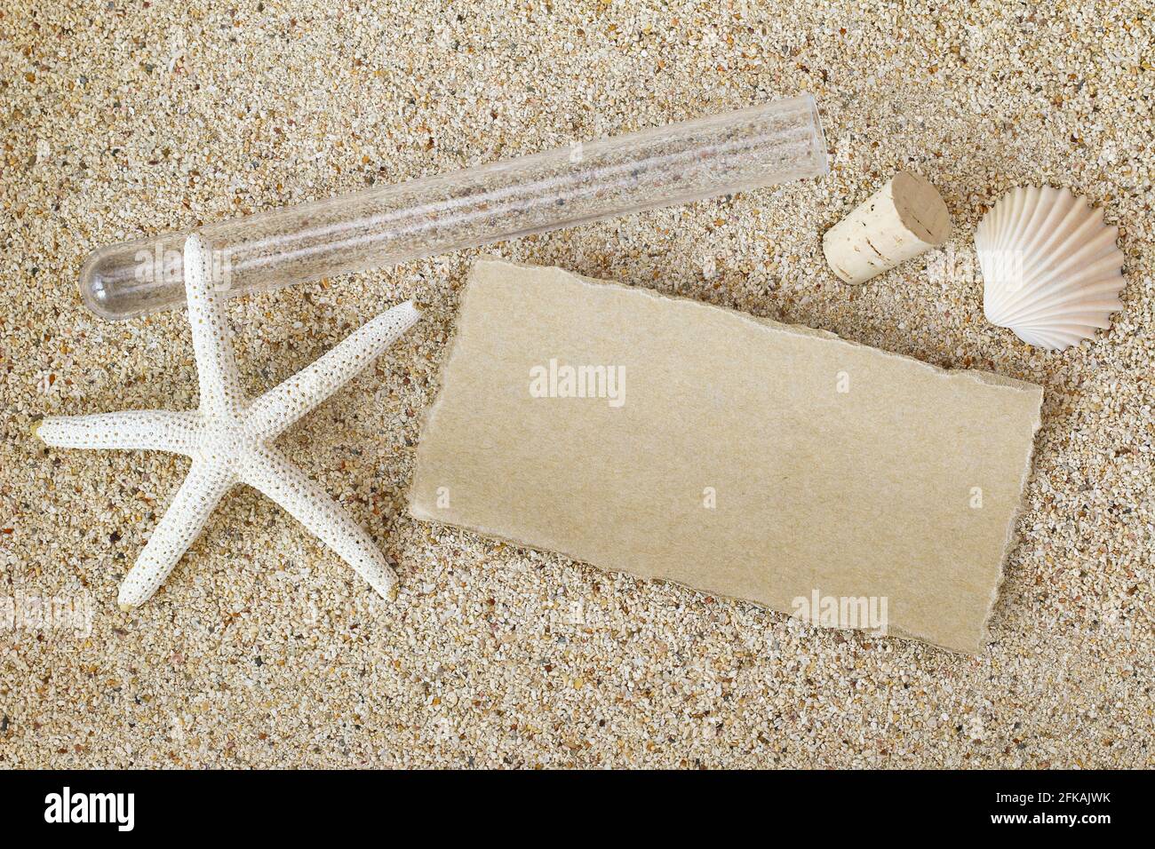Carta marrone bianca all'esterno di un tubo con coperchio di sughero rimosso su una spiaggia sabbiosa con stelle marine bianche e conchiglia. Messaggio in stile bottiglia Foto Stock