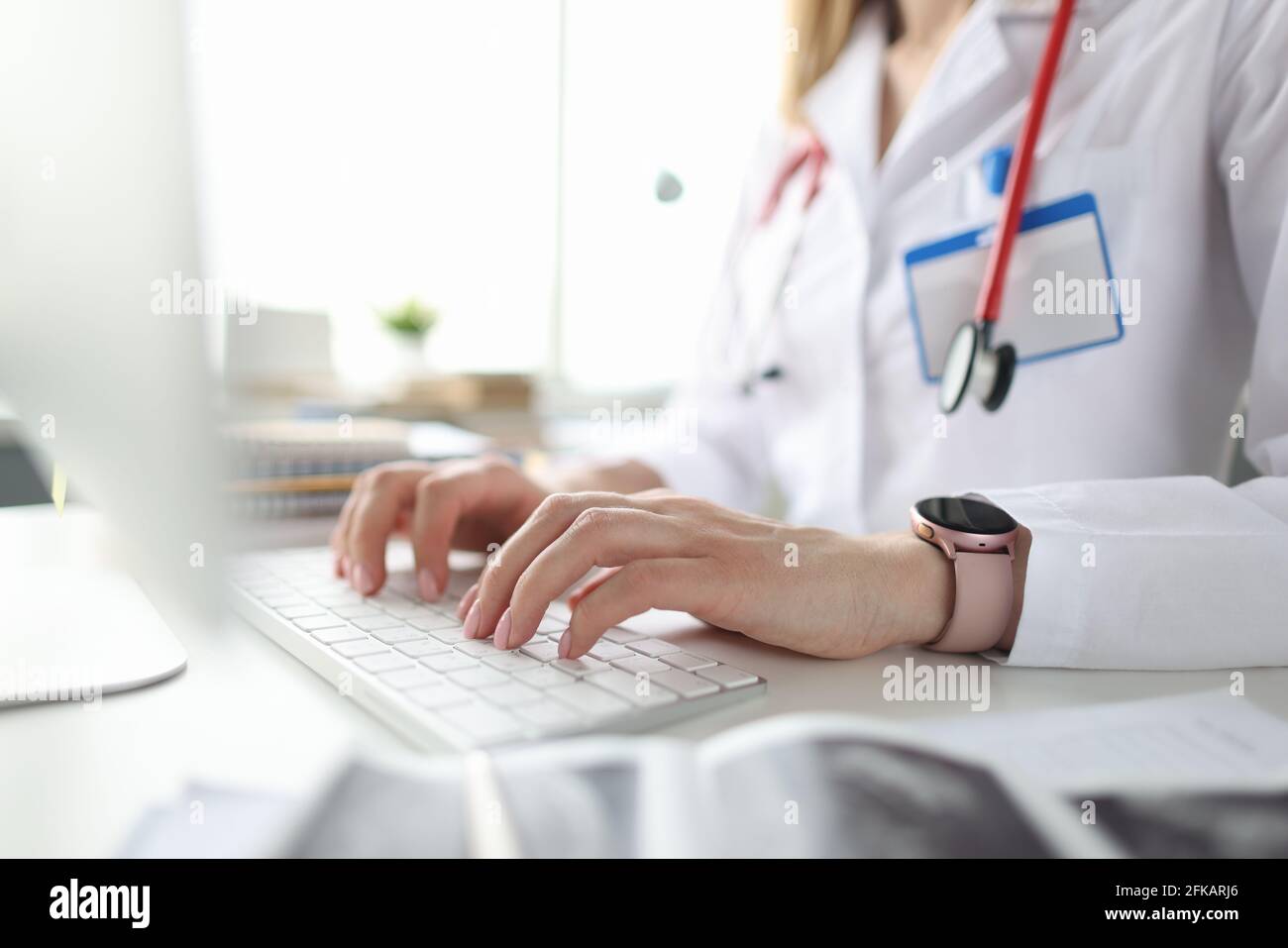 Medico seduto al tavolo e digitando sulla tastiera del computer closeup Foto Stock