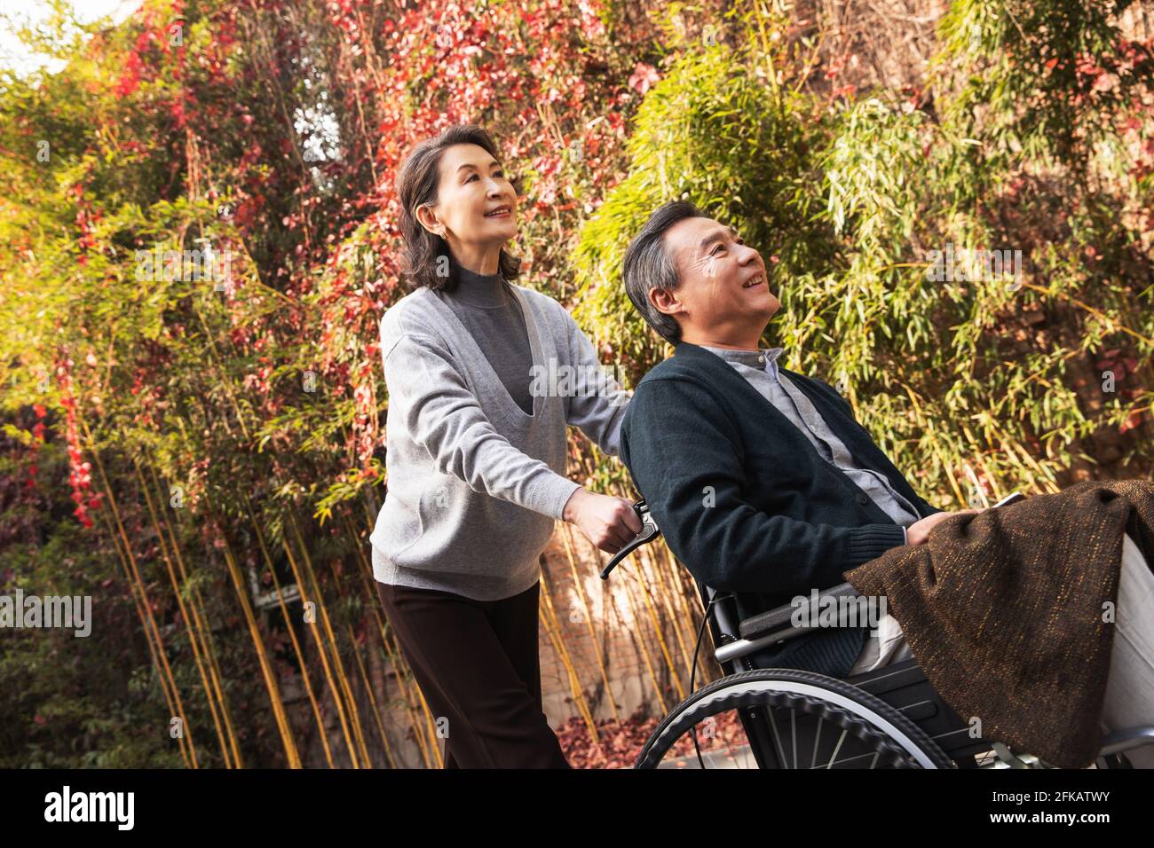 Sua moglie di donne anziane che spingono una sedia a rotelle Foto Stock